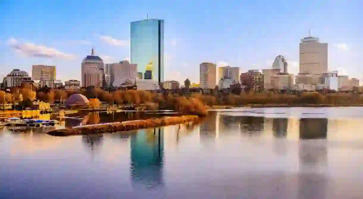 Boston City Skyline over the Charles River in Massachusetts, USA. A tranquil riverscape of Back Bay with golden illuminated wintery foliage in New England.