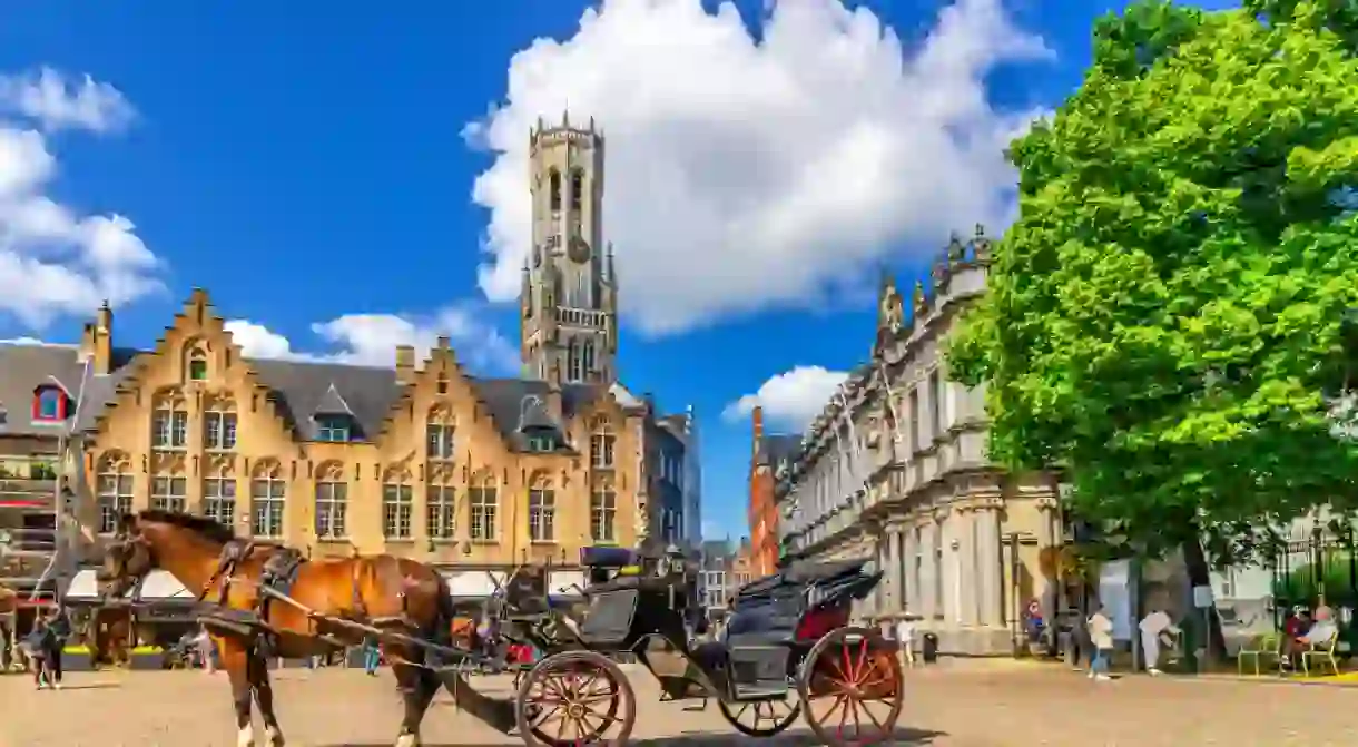 Horse-drawn carriage cart on cobblestone Burg square, medieval buildings and Belfry of Bruges Belfort van Brugge bell tower in Brugge old town, Bruges city historical centre, Flemish Region, Belgium