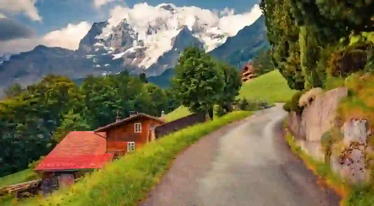 Empty asphalt road in Wengen village big snowy peak on background.Wonderful summer view of Swiss Alps, Bernese Oberland in the canton of Bern, Switzerland, Europe. Travel the world.