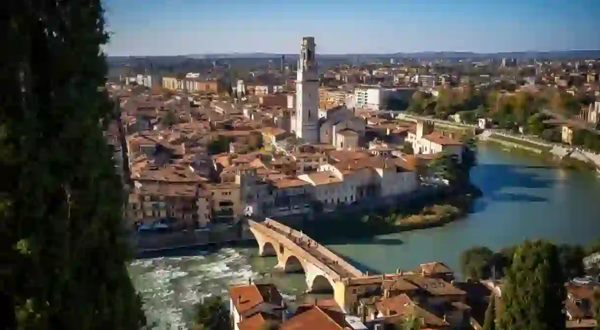 Aerial view of historic Verona city center, Ponte Pietra bridge crossing Adige river, Verona Cathedral, Duomo di Verona, red tile roofs, Veneto region, Italy. Panoramic view of the city of Verona.