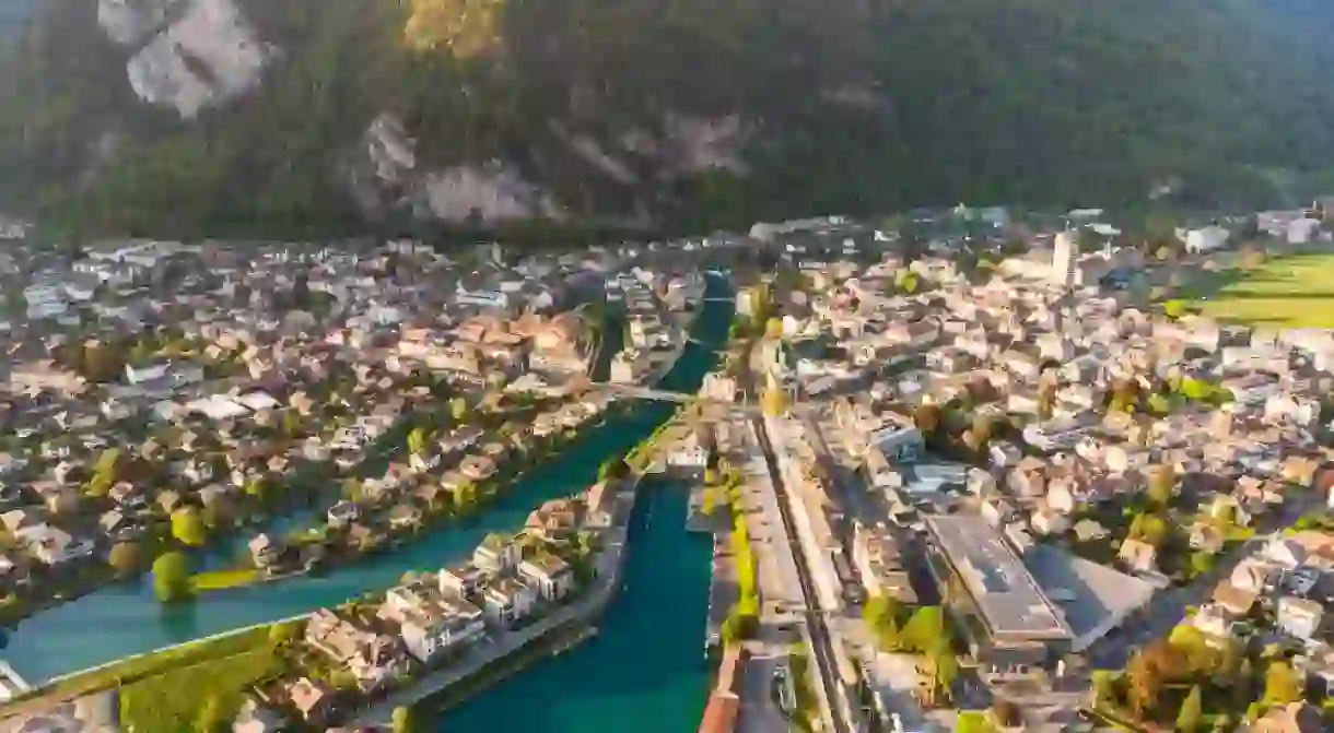 Interlaken, Switzerland: Aerial drone view of the Interlaken old town with the Aar river, the market square, the train station and cruise terminal in Canton Bern