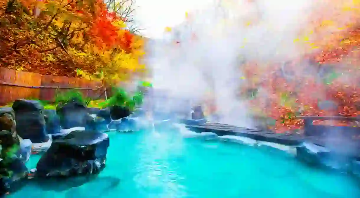 Japanese Hot Springs Onsen Natural Bath Surrounded by red-yellow leaves.