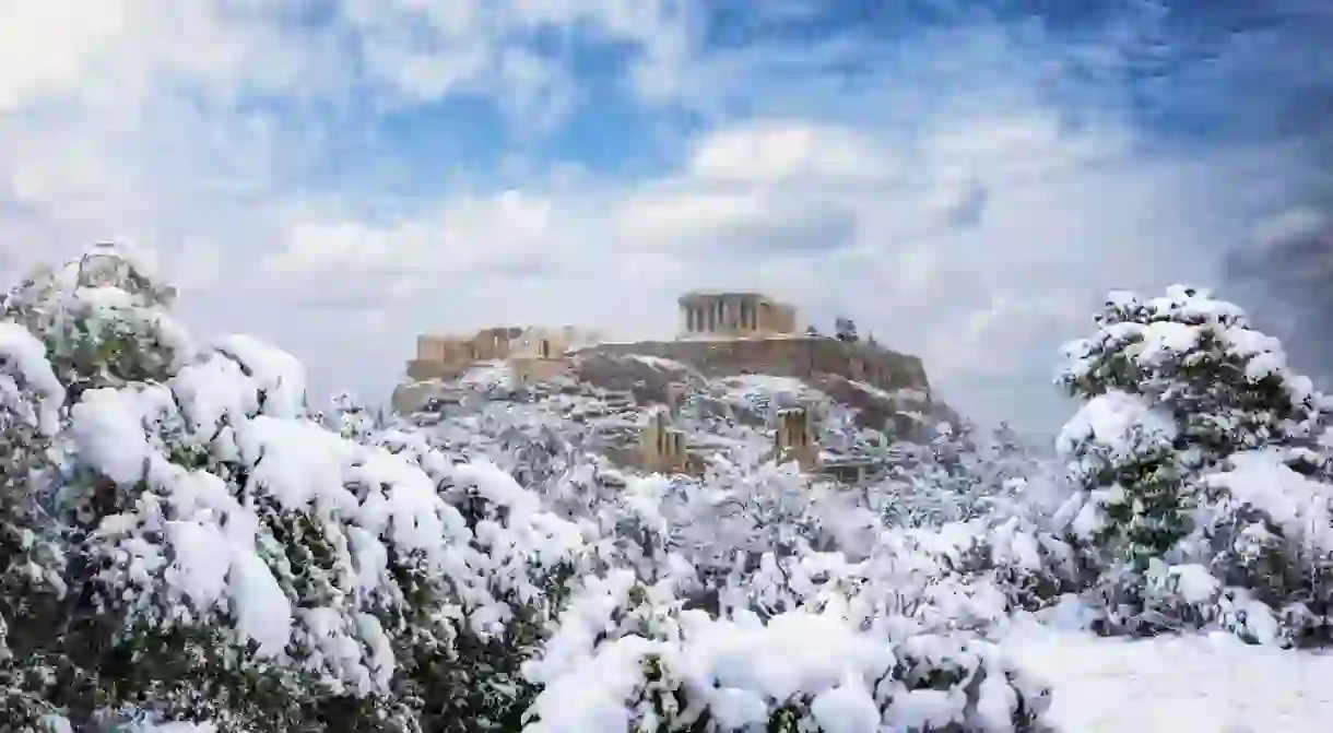 Beautiful view to the Parthenon Temple at the Acropolis of Athens, Greece, with thick snow and blue sky during winter time