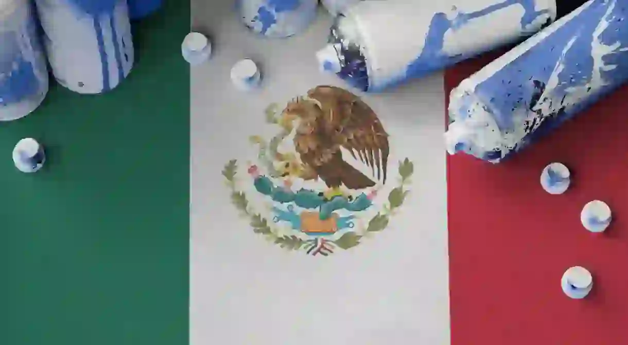 Mexico flag and few used aerosol spray cans for graffiti painting.