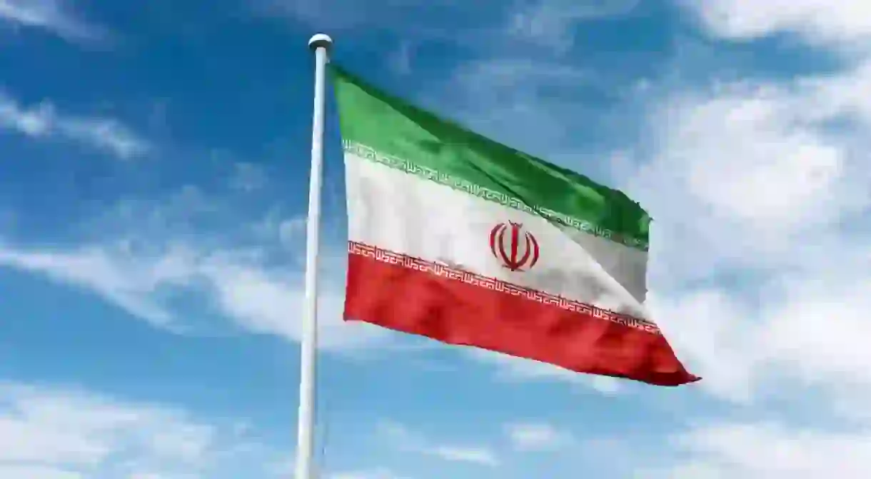 Iran flag waving at cloudy sky background. Islamic republic of Iran flag.