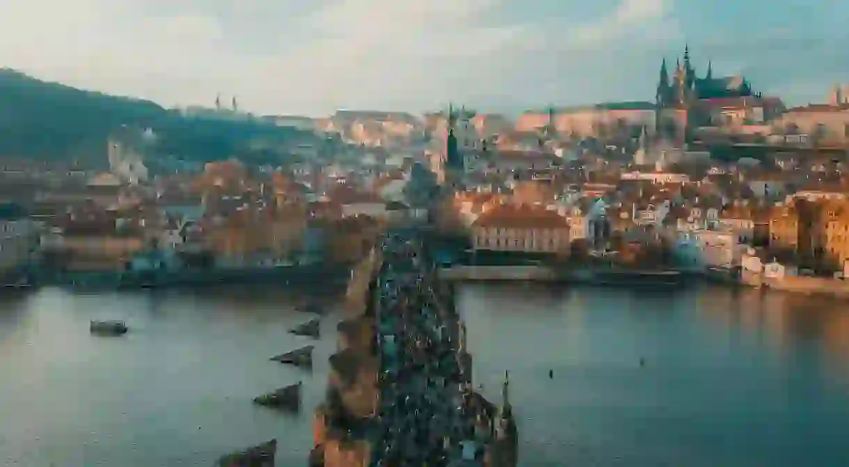 People walking across the Prague bridge