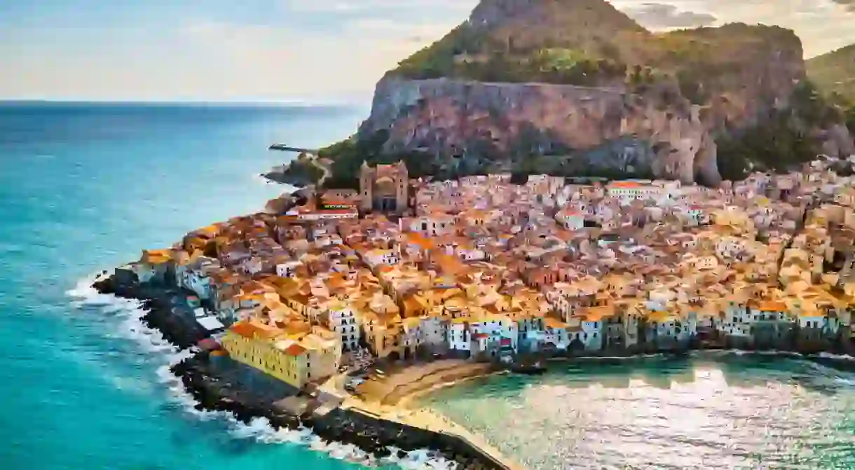 Drone view from above at the old town of Cefalu at sunset, medieval village of Sicily island