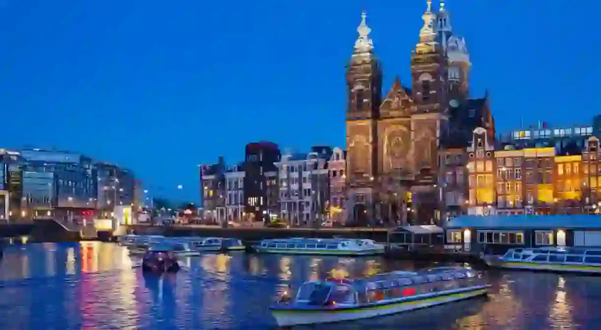 Basilica of Saint Nicholas with canal cruise in Amsterdam at night, Netherlands