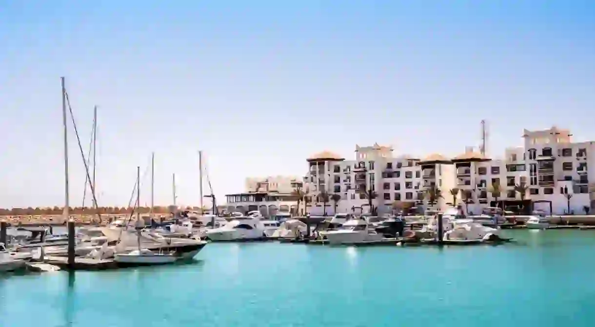 Agadir Marina in Morocco. Popular tourist area with luxury apartments, boats in harbor, shops and restaurants.