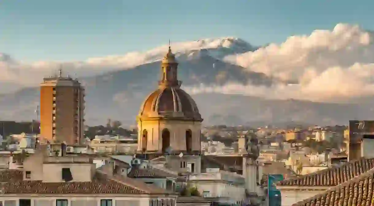 Catania cityscape with the view of Etna volcano at sunset in Sicily, Italy.