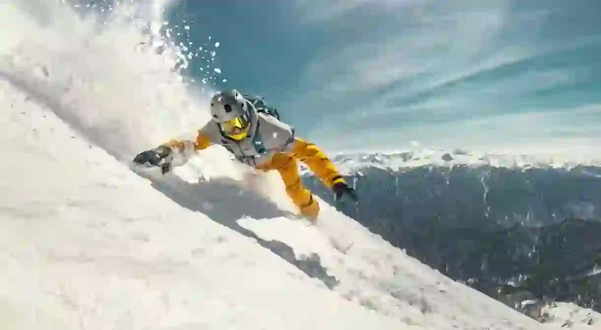 Real professional snowboarder rides at off-piste ski slope.