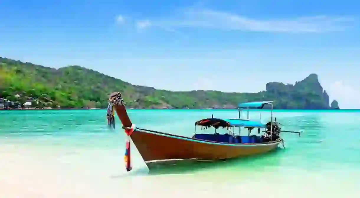 Thai traditional wooden longtail boat and beautiful white sand beach at Koh Phi Phi island in Krabi province.