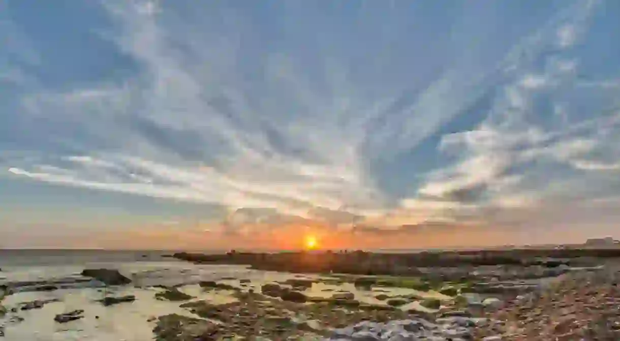 Uruguayan wild lonely beaches and idyllic sea landscapes at Uruguay coastline. Here we can see the sunset at La Paloma beach, the sun goes down behind the rocks above the water horizon over the sea