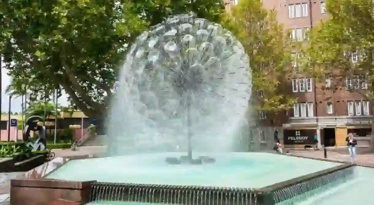 El Alamein fountain at Fitzroy Gardens in Sydney, with commercial properties and people.