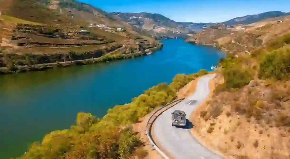 Lifestyle photo of a black Land Rover Discovery 4 driving along scenic Portuguese coastline.