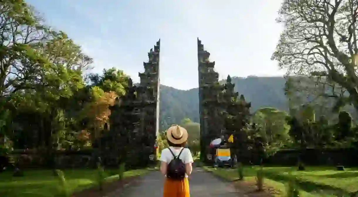 Woman tourist traveler with backpack enjoying walk through Balinese Hindu temple during vacation in Asia.