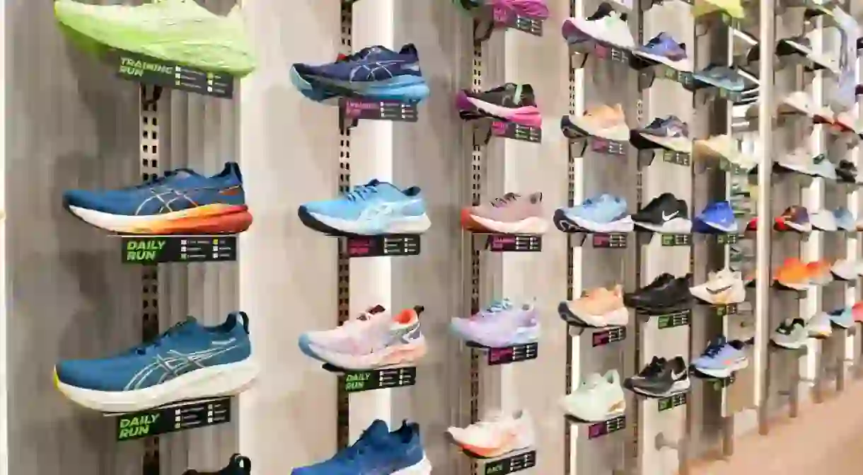 ASICS Running shoes are against the wall on display at a running shoe specialty store. ASICS is a Japanese sports shoes equipment and sportswear.